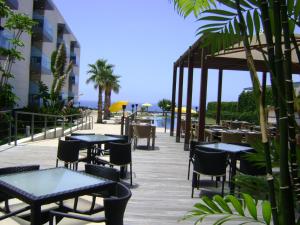 a restaurant with tables and chairs and the ocean at Golden Residence Hotel in Funchal