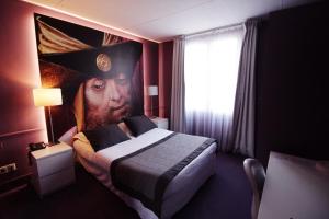 a bedroom with a bed with a painting of a man at Hôtel Cecyl Reims Centre in Reims
