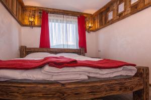 um quarto com uma cama de madeira e cortinas vermelhas em Jaworczański Raj pod Wysoką - z Sauną pzy Wyciągu em Szczawnica