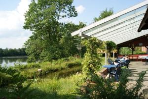 two people sitting at a table on a deck next to a river at Hotel Seelust in Hennstedt