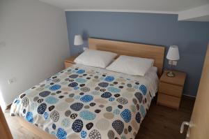 a bedroom with a bed with a blue and white comforter at Apartments Ostanek 2 in Portorož