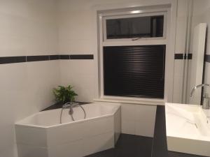 a white bath tub in a bathroom with a window at Aan't Kanaal in Harlingen