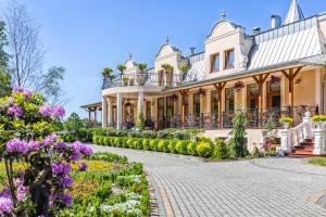 a large house with flowers in front of it at Leśna Perła - Restauracja i Pokoje Hotelowe in Rudzinitz