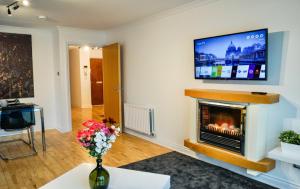 uma sala de estar com lareira e uma televisão de ecrã plano em Hydro Apartment with free car park em Glasgow