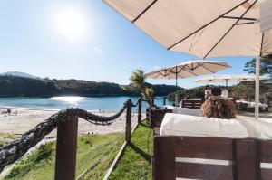 una mesa con sombrilla y una playa en Hotel La Farola del Mar, en Póo