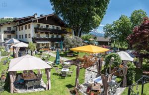 eine Außenterrasse mit Tischen, Stühlen und Sonnenschirmen in der Unterkunft Ferienhotel Lindenhof in Leogang