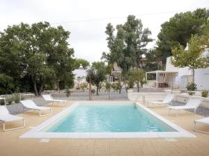 a swimming pool with white chairs and a pool at iTrulliescape in Locorotondo