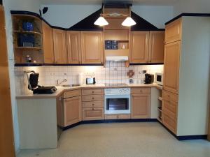 una cocina con armarios de madera y electrodomésticos blancos en Lukas Oscar, en Bad Blumau