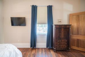 a bedroom with a dresser and a window with blue curtains at Crescent City Cottage in New Orleans