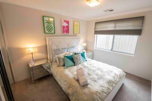 Un dormitorio con una cama con almohadas azules y una ventana en Magnificent Beach Retreat, en Jindalee