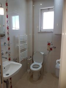 a white bathroom with a toilet and a sink at Olympia in Kharmanli