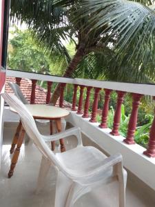 een tafel en stoelen op een balkon met een palmboom bij Casa De Olga in Vagator