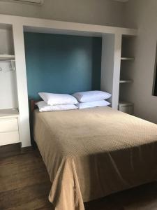 1 dormitorio con 1 cama con cabecero azul y almohadas blancas en Residencial Sol e Lua, en Palhoça