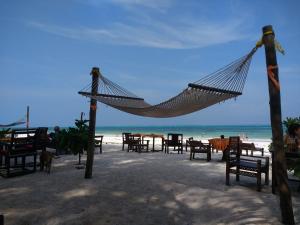 a hammock on a beach with tables and chairs at Mama Njoe Lodge in Kiwengwa