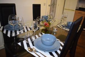 una mesa de comedor con copas de vino y un tazón. en Silverburn new house with free parking and nice garden en Glasgow
