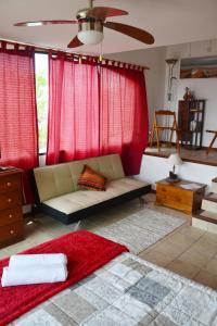 sala de estar con sofá y cortinas rojas en Hogar del Viento, Piscina Privada y Vista panorámica al Mar, en Piriápolis