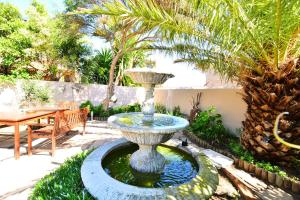 a fountain in a yard with a table and palm trees at Secret Garden Guesthouse in Bloubergstrand