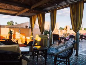 a living room with chairs and tables and windows at Riad Golf Stinia 1 in Meknès