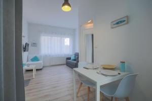 studio marine 100m plage في رويان: غرفة معيشة بيضاء مع طاولة وكراسي بيضاء