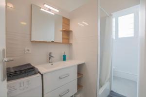 La salle de bains est pourvue d'un lavabo, d'un miroir et d'une douche. dans l'établissement studio marine 100m plage, à Royan