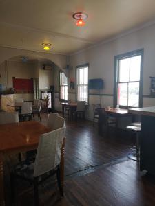 a dining room with tables and chairs and windows at Golden Cross Hotel in Waihi