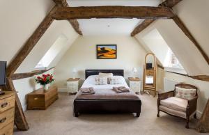 um quarto com uma cama e uma cadeira num sótão em Bantam Tea Rooms em Chipping Campden