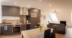 a kitchen and living room with a table and a couch at Résidence le XV in Bagnères-de-Bigorre
