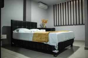 a bedroom with a black bed with a yellow blanket at Hotel Escorial Ibague in Ibagué
