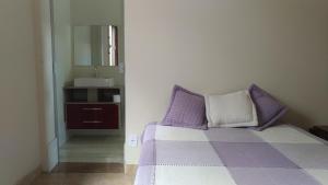 een slaapkamer met een bed met een spiegel en een wastafel bij Quarto e suíte para uma pessoa in Alfenas +7 foto's