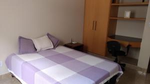 a bedroom with a purple and white bed and a desk at Quarto e suíte para uma pessoa in Alfenas