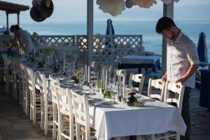 un hombre parado frente a una mesa larga en Lido Hotel, en Xylokastro