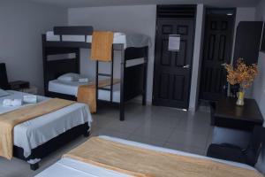 Zimmer mit 2 Etagenbetten und einem Zimmer mit einem Tisch in der Unterkunft Hotel Escorial Ibague in Ibagué