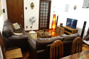 sala de estar con muebles de cuero y TV de pantalla plana en Apartamento 3 quartos Rio, en Río de Janeiro