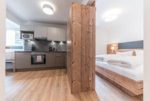 Cet appartement comprend une chambre avec une cloison en bois dotée d'un lit et une cuisine. dans l'établissement Hochstatt Appartements, à Sölden