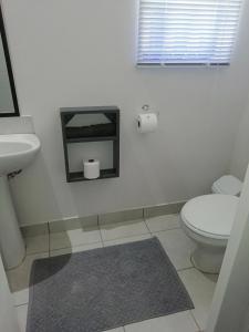 a white bathroom with a toilet and a sink at Middelplaas Paarl Guesthouse in Paarl