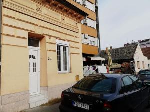 une voiture noire garée à côté d'un bâtiment jaune dans l'établissement FilinHome Papa Studio 1, à Novi Sad