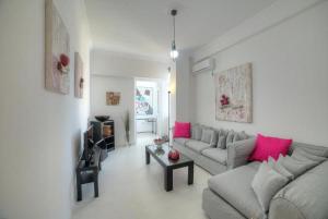 a living room with a gray couch and pink pillows at Cosy apartment in Glyfada center in Athens