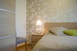 ein Schlafzimmer mit einem Bett mit einer Lampe und einem Stuhl in der Unterkunft Apartamentai Liuks in Druskininkai