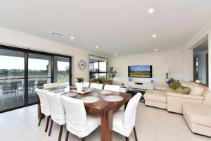 a living room with a wooden table and white chairs at Horizon 7 in Pokolbin