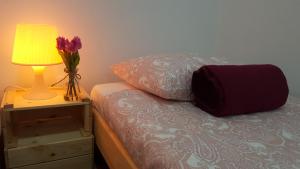 a bed with a vase of flowers next to a lamp at Casa dos Avós in Villa Nogueira