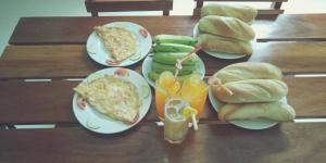 une table en bois recouverte de assiettes de sandwichs et de fruits dans l'établissement Phong Nha Amanda Homestay, à Phong Nha