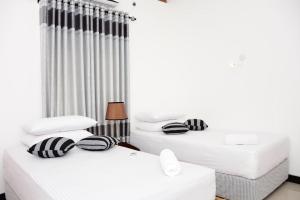 2 camas en una habitación con paredes blancas en Richmond Hillside, en Galle