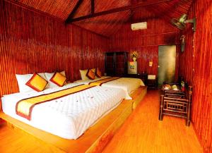 twee bedden in een kamer met rode muren bij Tam Coc Valley Bungalow in Ninh Binh