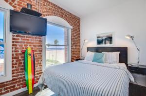 a bedroom with a bed and a brick wall at Venice Breeze Suites in Los Angeles