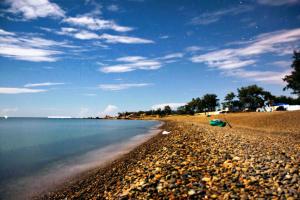 a beach with a green boat on the shore at Khách Sạn Đào Nguyên in Tuy Phong