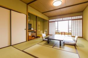 ein Wohnzimmer mit einem Tisch, Stühlen und einem Fenster in der Unterkunft Takahan in Yuzawa