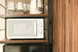 a microwave on a shelf with cups and mugs at Guest House Re-worth Yabacho1 401 in Nagoya