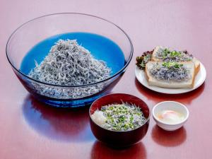 a table with a bowl of noodles and a plate of food at Sotetsu Fresa Inn Fujisawa Shonandai in Fujisawa