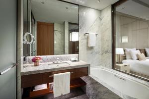 a bathroom with a tub and a sink and a bed at Lotte Hotel Seoul Executive Tower in Seoul