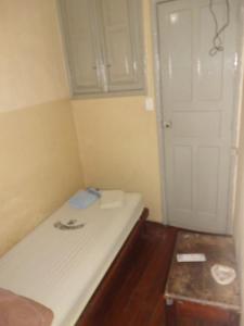 a small room with a white bed and a door at Hospedagem Ledo in Rio de Janeiro
